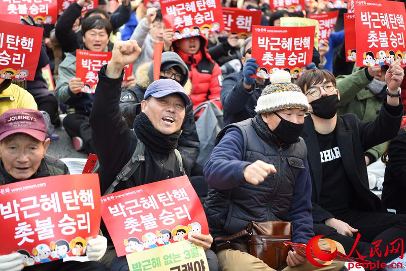 韩国民众在弹劾案通过后欢呼呐喊。裴埈基摄