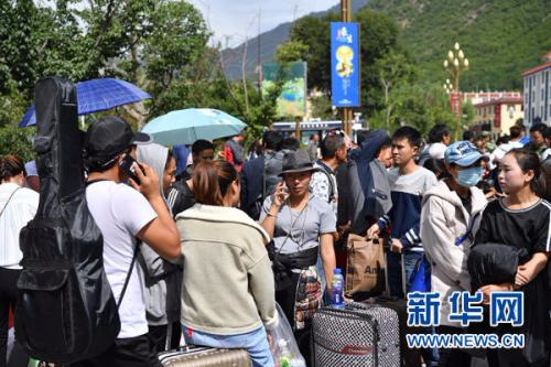 8月10日，在漳扎镇的灾民安置点，民宿及酒店工作人员和部分居民在道路旁等待乘车离开。新华社记者 李鑫 摄