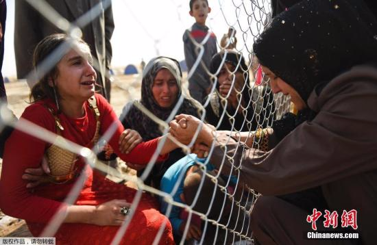 资料图片：难民隔着铁丝网相见。