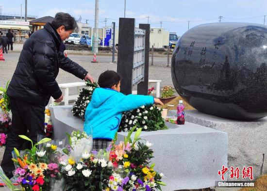 资料图：当年人员损失最为惨重的宫城县内各地，民众在当地建起的慰灵碑前献花祭悼。王健 摄