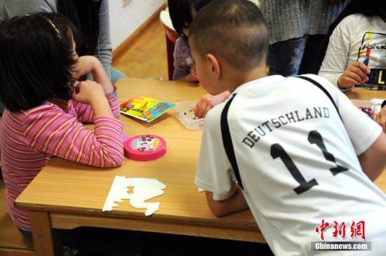 资料图：德国首都柏林一处难民收容所内，几名儿童在志愿者带领下做益智游戏。 彭大伟 摄