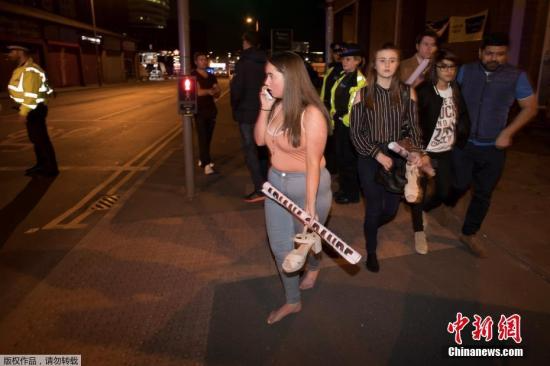 根据英国警方的最新消息，当地时间5月22日晚发生在曼彻斯特体育馆的爆炸事件，已经导致22人死亡，59人受伤。爆炸发生于当地时间22日晚10点35分，当时美国流行歌手阿丽安娜·格兰德(Ariana Grande)在曼彻斯特体育场的演唱会刚刚结束。图为爆炸发生后，被疏散的歌迷们手里还拿着明星的海报。