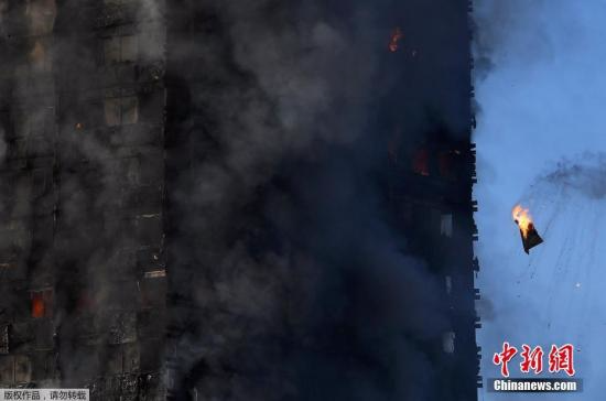 当地时间6月14日凌晨，伦敦西部一栋20余层的公寓大楼发生大火，火势猛烈，几乎蔓延到了所有楼层。约200名消防员和40辆消防车前往灭火。图为被烧毁的物品从楼上落下。