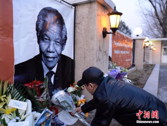 资料图：一名中国民众在位于北京的南非共和国驻华使馆外，向曼德拉的大幅画像敬献鲜花，对曼德拉的逝世表示哀悼。<span target='_blank' href='http://www.chinanews.com/'></div>中新社</span>发 侯宇 摄