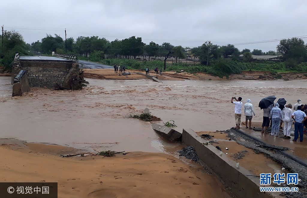 This photo taken on July 25, 2017 shows people gathering next to a washed away road in Deesa municipality, which has been hit by severe flooding along the Banas River in northern Gujarat state in western India. Indian rescue crews were working on July 26 to save flood victims and recover bodies in communities devastated by heavy monsoon flooding. The official death toll from the floods in the westernmost state stands at 111, with more than 36,000 people evacuated to safe areas as helicopters and boats try to reach those still stranded. STR
