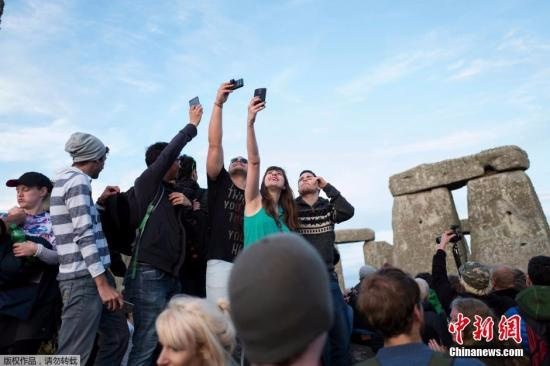 人们在巨石前高举手机自拍。