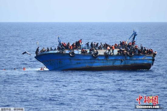 资料图片：利比亚近海海域，一艘满载难民的船只即将倾覆，船上的难民纷纷跳海逃生。