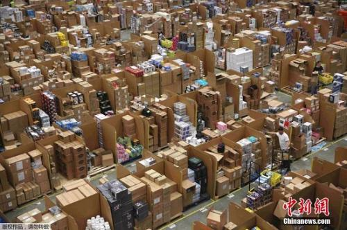 资料图：“黑五当天”，英国的一处亚马逊仓库内，工作人员正忙着给商品装箱。