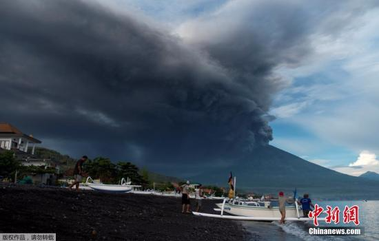 当地时间11月26日，印尼巴厘岛卡朗阿森，阿贡火山喷发。图为海边远眺火山喷发。