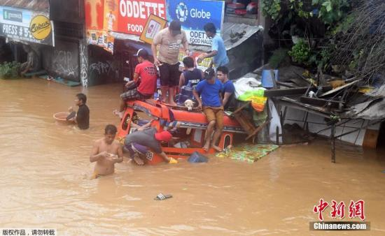 卡加廷德奥罗港口城镇的街道已经完全被淹没，民众爬到一个摩的上躲避洪水。