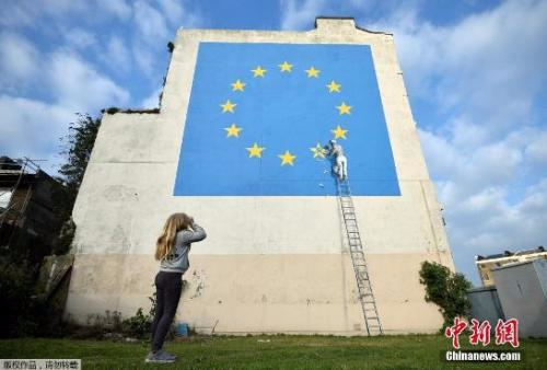 资料图：英国多佛，街头艺术家班克西创作了一幅画，画面中一名工人正从欧盟12星旗帜上抹掉一颗星，寓意着英国脱离欧盟。