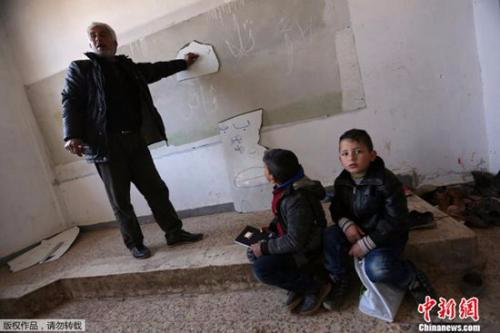 在位于阿勒颇北部的这所学校里，老师用破碎的白板讲课，而学生们坐在地上听课。
