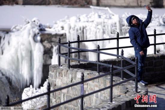 美国国家气象局气象学家布赖恩·赫尔利说，今后两天全美可能20多个地方会刷新低温纪录。图为当地时间1月2日，新泽西州东北部城市帕特森的居民Obdulio Arenas举起手机自拍，在他身后是在极寒天气中冻住的瀑布。