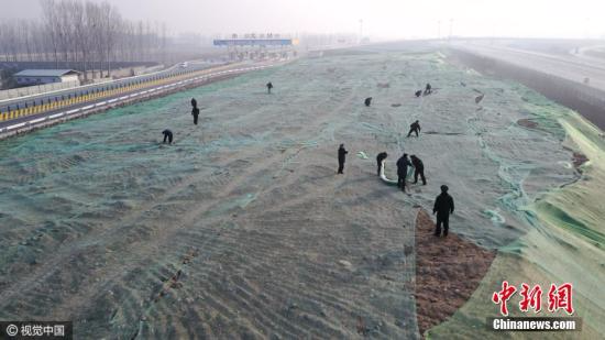 2016年12月16日，北京，大兴区安定镇京台高速安定出口处，城管队员正在苫盖建筑垃圾。图片来源：视觉中国