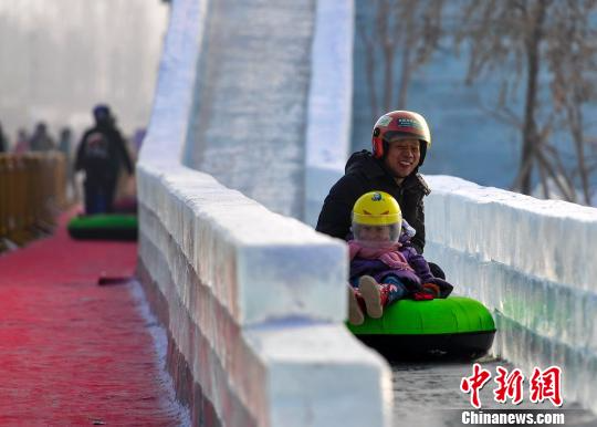 一位市民带着孩子感受冰滑梯的刺激。　刘新　摄