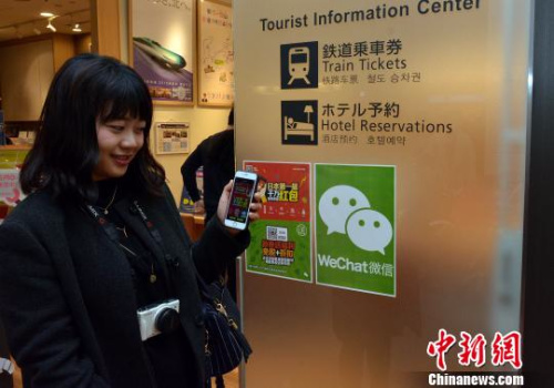 图为一名刚刚抵达的中国游客试着在羽田机场大厅“摇红包”。　东友 摄