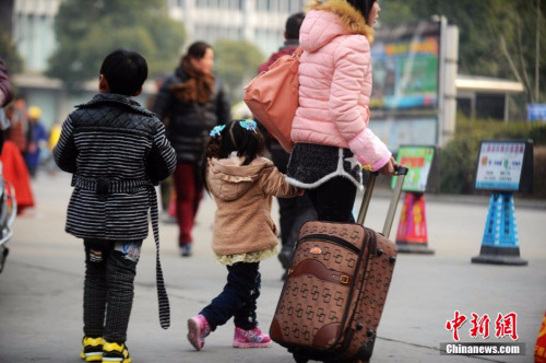 资料图：2015年2月5日，2015年春运第二天，江苏扬州市汽车西站迎来客流高峰，图为家长带着孩子在江苏扬州市汽车西站候车。 孟德龙 摄