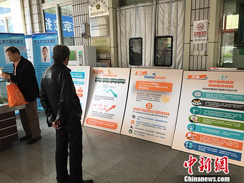 北京普仁医院外，有人在细读医改宣传板。汤琪 摄