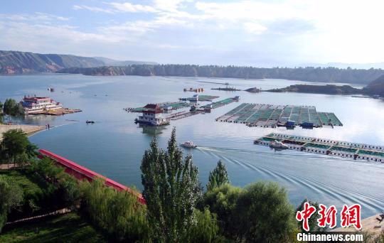 z资料图：一艘渔船驶过刘家峡水库网箱养殖区平静的湖面。罗玉珍 摄