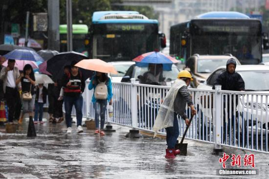 6月12日，贵阳持续降雨造成贵阳市多处路段严重积水，市民出行受阻。图为贵阳市环卫工人清理路面积水。 黄芷昕 摄