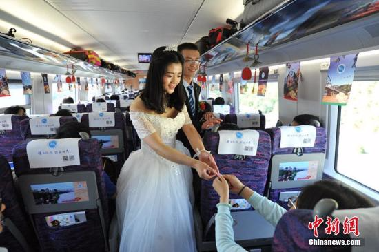百对新人宝兰高铁上举行集体婚礼开启蜜月之旅。图为新人向旅客送上喜糖。杨艳敏 摄