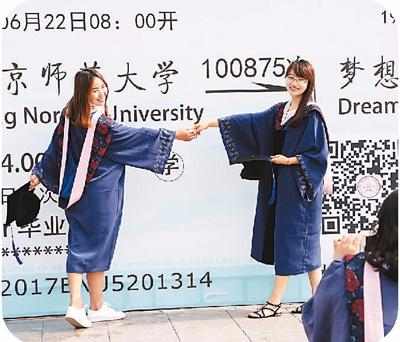 北京师范大学的两名毕业生在毕业背板前合影。新华社发
