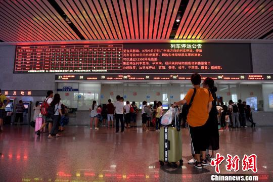 8月23日，广西南宁东站售票大厅内，两名旅客驻足观看列车停运信息。　俞靖 摄
