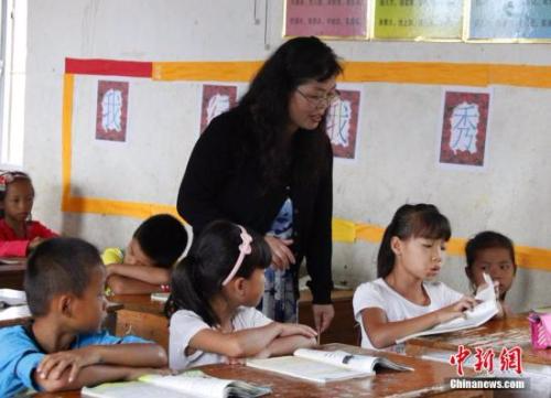 9月22日，在偏远山区的广西柳江县穿山镇六庙小学，几间瓦房教室、宿舍，操场上3张乒乓球台就是学生和老师的一切。48岁的韦凤玲在给学生们上课，“下雨时，人在上课雨从头顶落”，韦凤玲这样形容学校环境。2014年从老挝完成两年支教任务的柳江县第二中学教师韦凤玲，又到该县土博镇、穿山镇村级小学支教，被称为支教“专业户”。朱柳融 摄