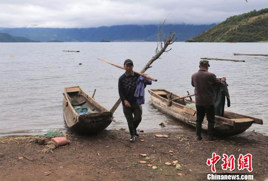 9月22日，两位摩梭渔民在泸沽湖上下网捕鱼后上岸。　王磊　摄