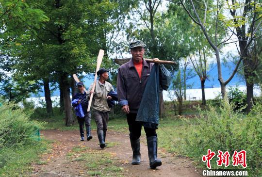 9月22日，摩梭渔民们扛着撸走回泸沽湖岸边的家。　王磊　摄
