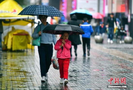 资料图：9月24日，新疆乌鲁木齐市降下秋雨，外出民众打着雨伞快步前行。 <span target='_blank' href='http://www.chinanews.com/'></div>中新社</span>记者 刘新 摄
