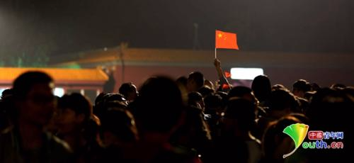 人潮中，一位游客举起手中的国旗。 中国青年网记者 孙钊 摄
