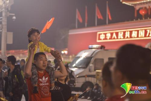 一位父亲将孩子扛在肩膀上路过天安门城楼。 中国青年网记者 李永鹏 摄