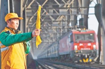 护桥工举起手中的黄旗向列车示意通过。
本报记者 程远州摄