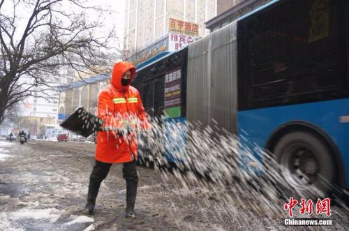 1月4日凌晨3点郑州市的环卫工人们就到岗除雪。图为环卫工人在街头撒融雪剂。 韩章云 摄