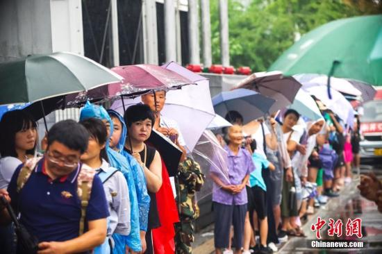 8月12日，游客冒雨在清华大学校门外排队等候入校参观。暑假以来，不少游客带着子女蜂拥至北京大学、清华大学等高校，一睹中国最高学府的风采。 <span target='_blank' href='http://www.chinanews.com/'></div>中新社</span>记者 贾天勇 摄