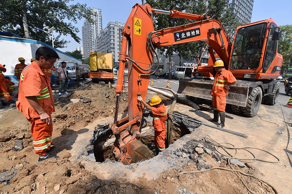 烈日下，抓紧抢修路面塌陷的市政抢险人员。（人民网记者 翁奇羽 摄）