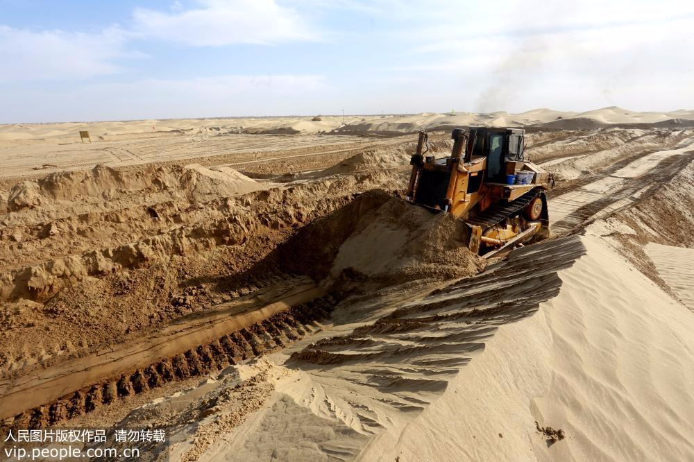 2017年11月17日，一辆大型推土机在富达林果业科技开发公司的基地将沙漠沙丘一点点推平。